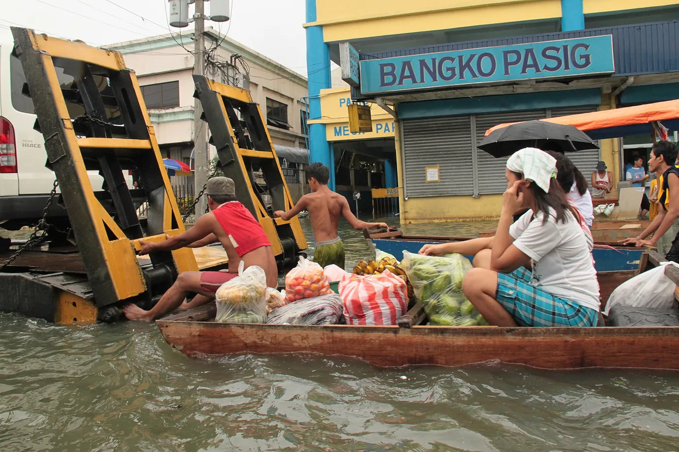 Residents move supplies by boat along a flooded street in Pasig in September 2009